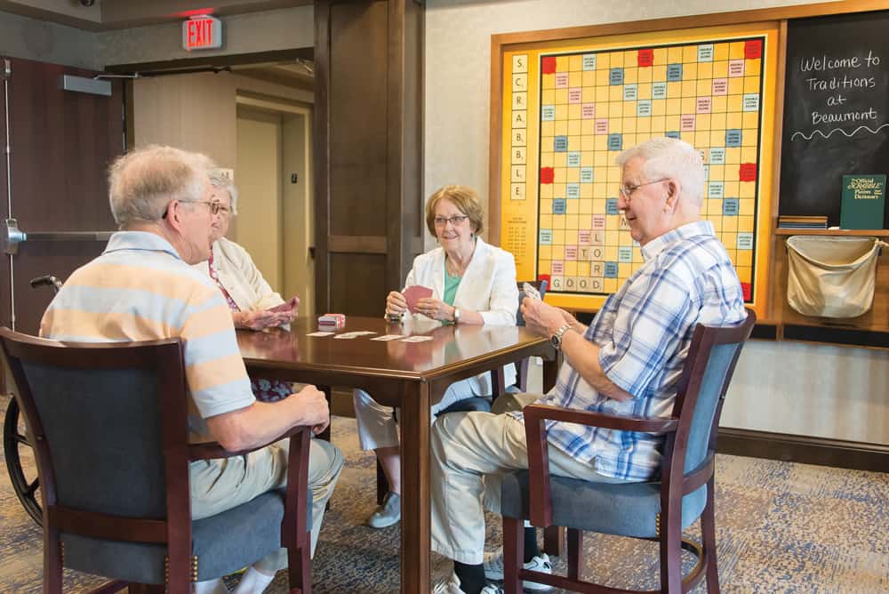 Four seniors are playing cards at the table