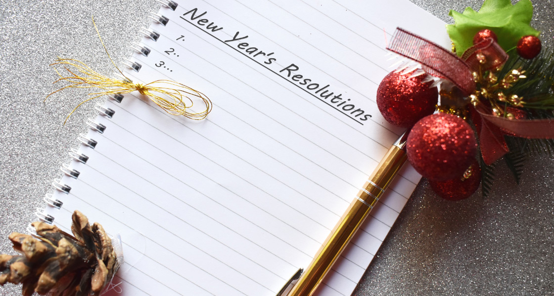 A notepad has the words "New Years Resolutions" along with a pen