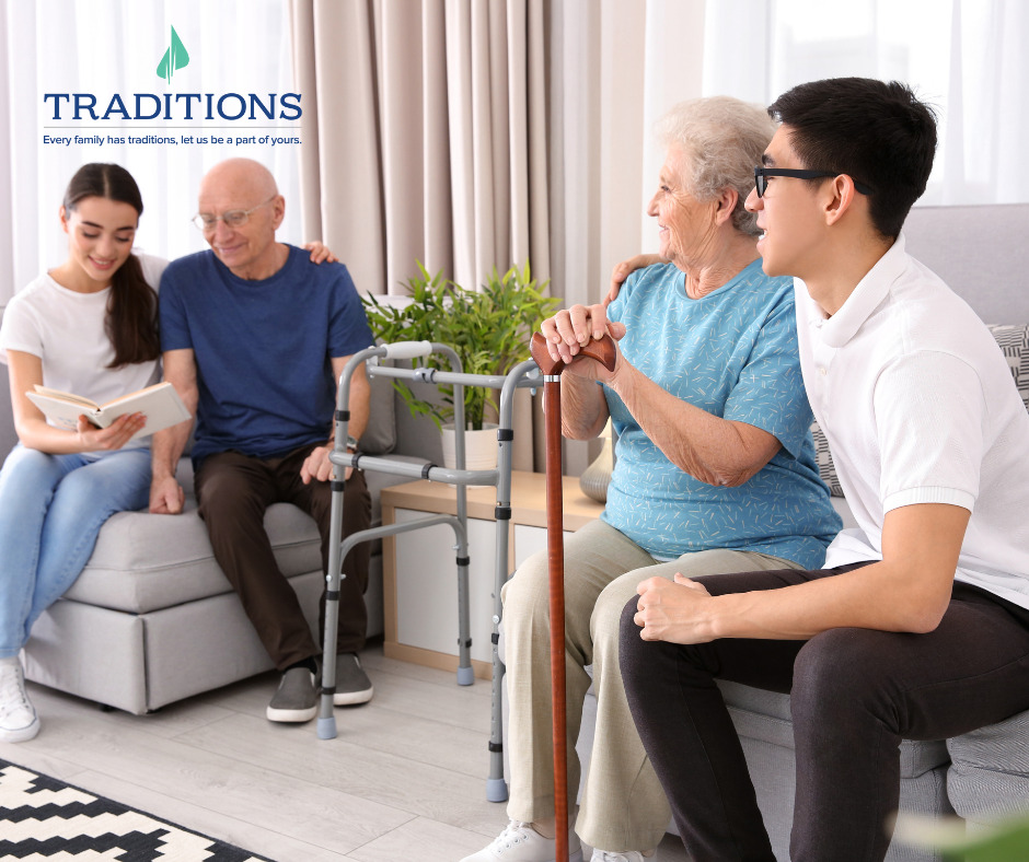 A teen girl sits with her grandfather reading a book and a teen boy sits with his grandmother looking in the distance