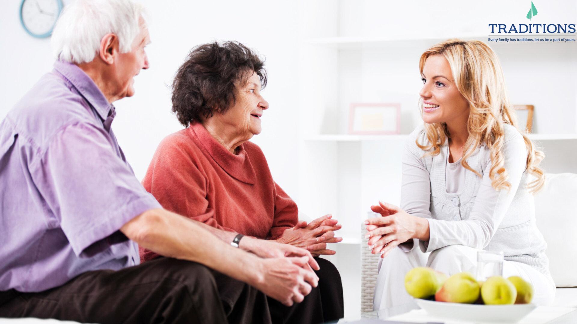 A woman in white speaks with her elderly parents