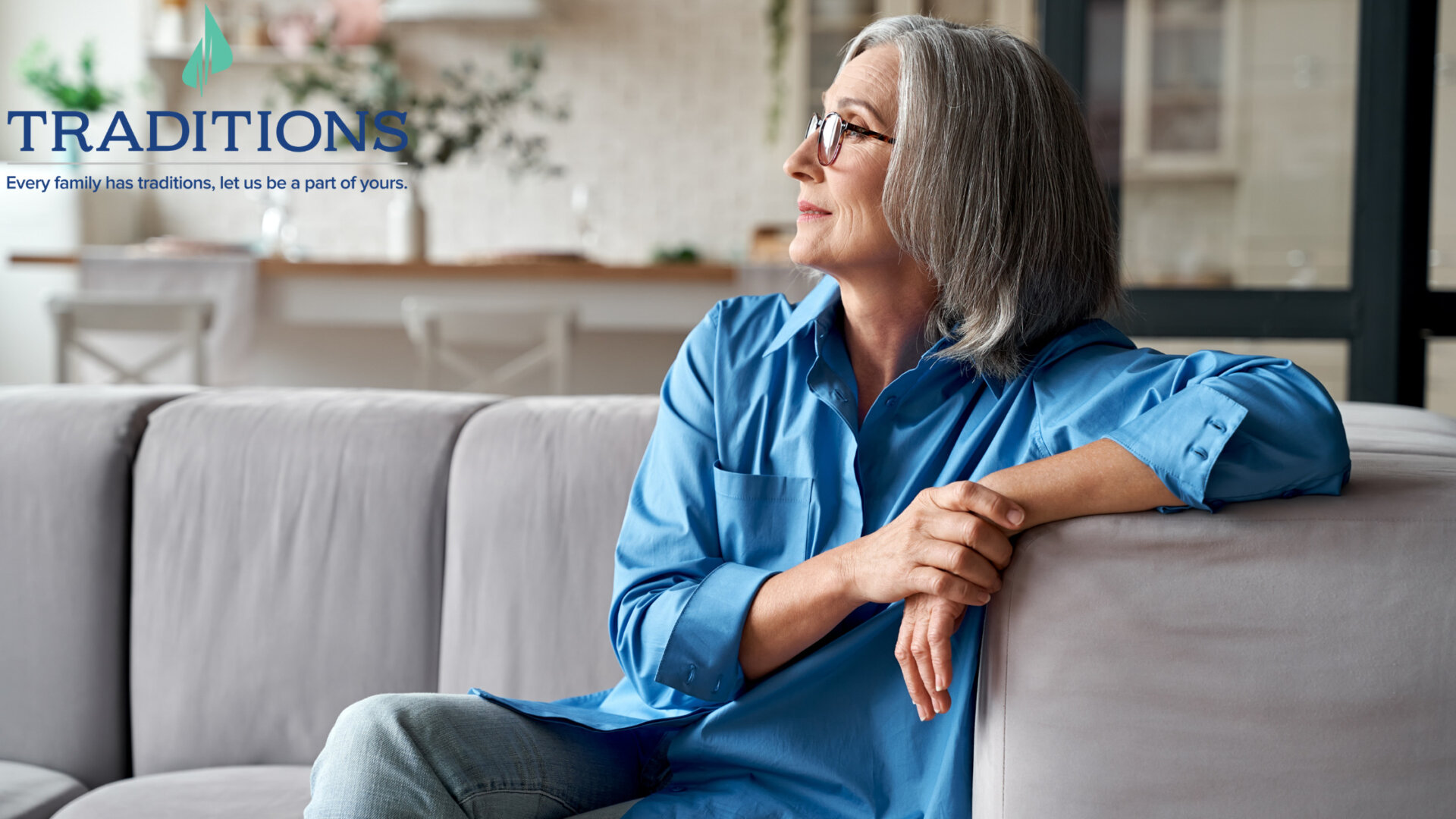 A woman in blue sits on the couch while looking onward