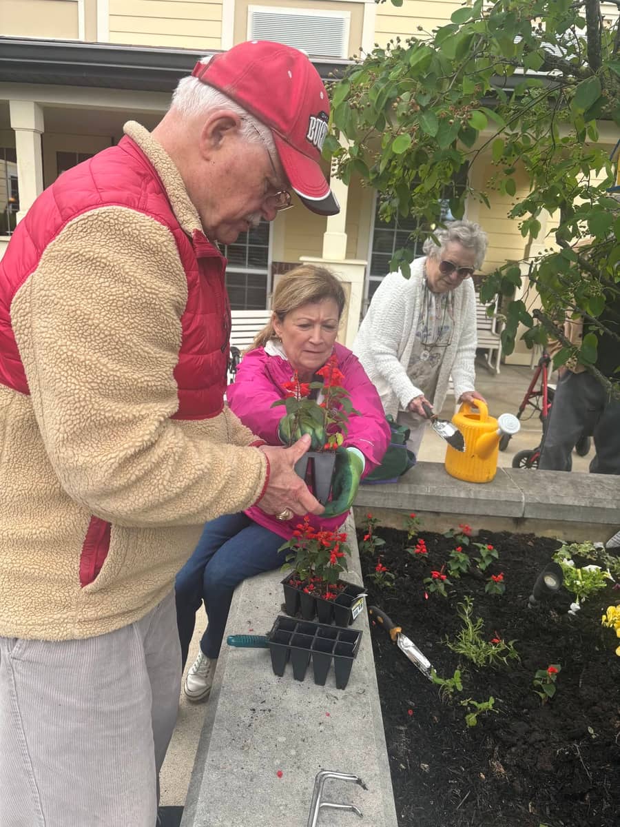 Residents planting flowers together in the community garden at Meadow Brook Senior Living