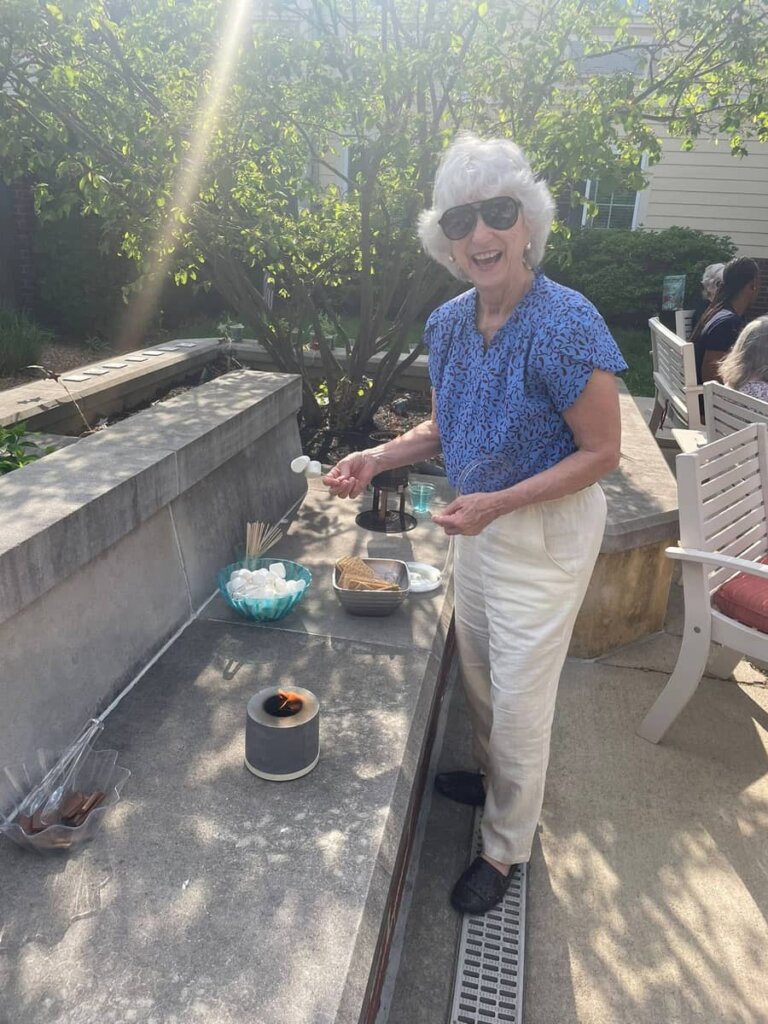 Smiling resident roasting marshmallows during an outdoor social activity at Meadow Brook Senior Living