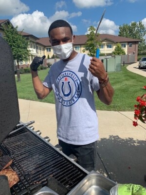 A young man in a gray shirt is using the grill